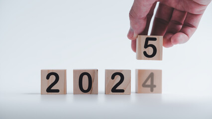 hand holding wooden cubes with the text 2025 2024 over background to change or translated from 2024...