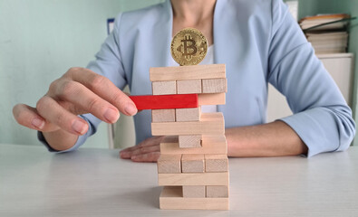 Woman Playing Jenga Game With Bitcoin on Top of Tower