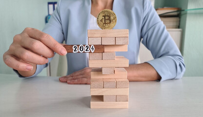 Person Playing Block Stacking Game With Bitcoin Coin and 2024 Year Marker