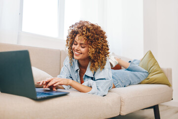 Happy woman working on laptop in cozy living room, surrounded by modern technology and comfortable lifestyle