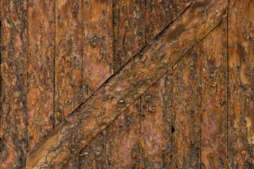 Close-up color photo of a textured rustic pine log wall with a decorative diagonal board.