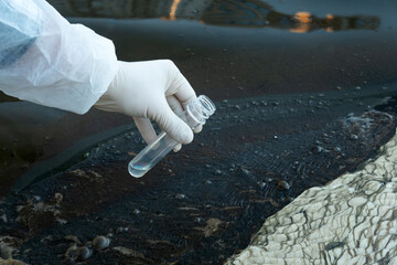 Scientists with protective suit holding a test tube with sample water in their hands. Water...