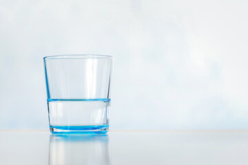 blue glass with clear water on a blue background. Clear and full glass of water. copy space