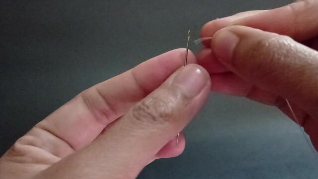 Hand inserts thread into needle