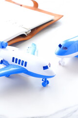 離陸を待つ旅客機と、開いたノートで、旅行を計画しているイメージ
