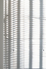 White wall with window with long shadow of blinds.