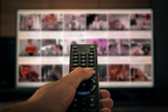 Porn TV pornography. remote control in a man's hand on the background of an erotic movie in out of focus. adult content on the cable channel in the hotel