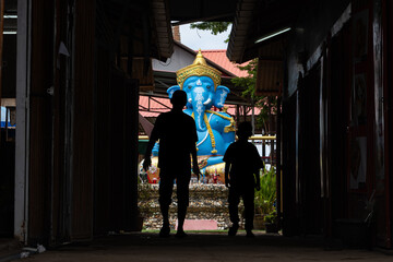 People walk through a narrow lane to the colorful elephant – Lord Ganesha