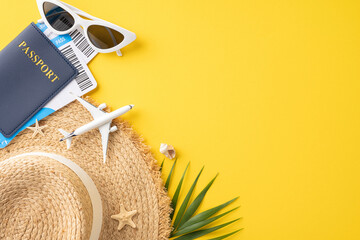 Top view of summer travel essentials including passport, hat, sunglasses and airplane model on yellow background