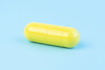 Yellow turmeric therapeutic capsules, herbal vitamin pill or drugs for treatment on blue background, medicine and healthcare concept, close-up view.