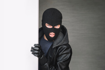 the thief looks out from around corner, copy space. thug keeps the front door Maniac broke into the...