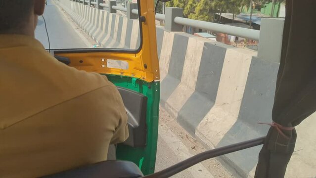 POV of a tourist person travelling in an auto rikshaw taxi while the driver cruises along the highway road in india 