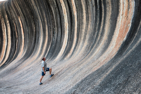 Man looking up at bizarre rock formation, Wave Rock, Western Australia