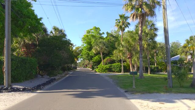 Driving on Florida scenic road. Car point of view of Casey Key coastal neighborhood with tropical nature and southern architecture.