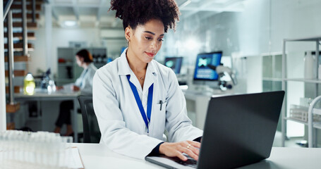 Scientist, woman and typing on laptop in laboratory, medical professional and bioinformatics...