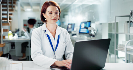 Scientist, woman and typing on laptop in lab, medical professional and bioinformatics analysis...