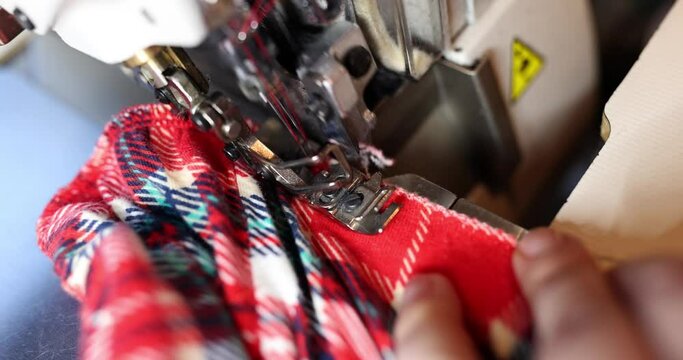 Sew seam of a flannel shirt in red checkered pattern using sewing machine