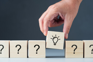 Hand put a wood cube with light bulb symbol into the row of many questions, good answer for the all...