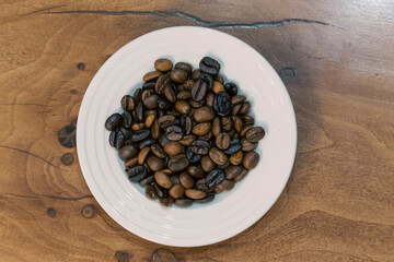 Roasted coffee beans on a white saucer implying the concept of coffee trade and business in prefect...