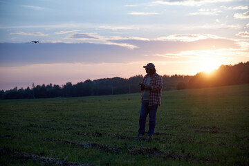 a man launches a drone at sunset in a field