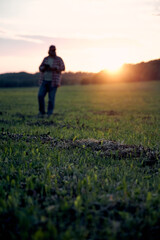 a man launches a drone at sunset in a field
