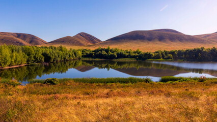 Reflection of the Karamuruntau ridge on a lake on the Yuldybaeva River in the southern Urals on a summer sunny day