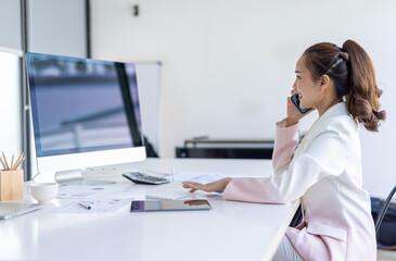 Asian Businesswoman Using laptop computer and working at office with calculator document on desk, doing planning analyzing the financial report, business plan investment, finance analysis concept.
