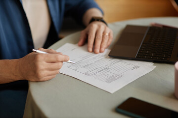 Close up of unrecognizable senior woman signing financial papers and doing taxes at home copy space