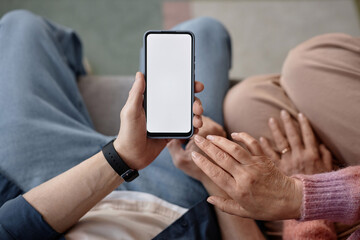 Top view closeup of senior couple holding smartphone with blank white screen mock up and using mobile app copy space