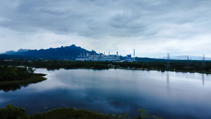 Landscape of the Mae Moh coal-fired power plant in Lampang, Thailand, with a view of the reservoir and a sky with clouds.