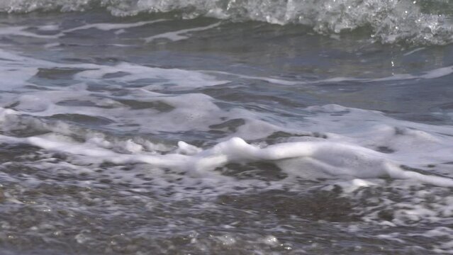 Close-up live-action video of waves crashing on a sandy beach
