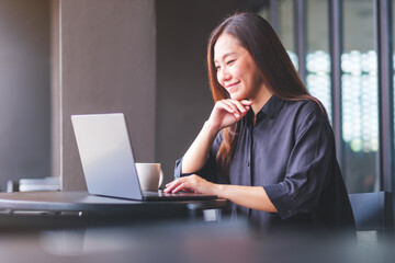 Portrait image of a young woman working on laptop computer in cafe