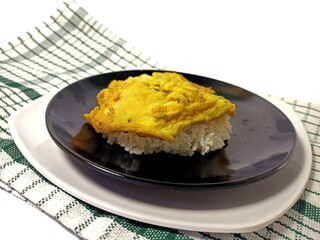 Rice with omelet on black plate, nutritious breakfast