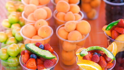 Juicy fruits and berries in plastic cups, perfect for a hot day refreshment
