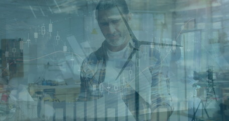Image of graphs and financial data over wind turbine and caucasian male engineer