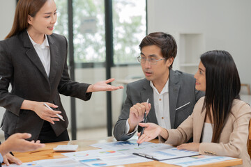 Group of Asian businessmen are presenting graphs on a whiteboard.