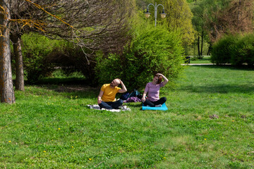 A couple in the park does yoga.