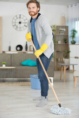 full length of young man mopping floor at home