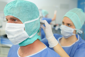 an assistant securing surgeons mask