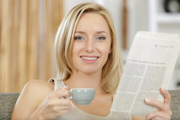 young beautiful woman reading the newspapers and drinking coffee