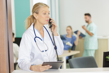 female doctor using tablet at desk having phone call