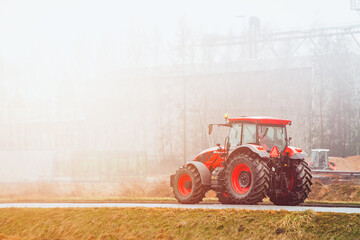 Modern farming tractor working in misty countryside field