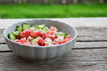 Traditional Bulgarian shopska salad with  tomatoes ,cucumbers and cheese on wooden board