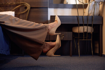 Legs wearing high-heels of relaxed businesswoman resting in hotel room