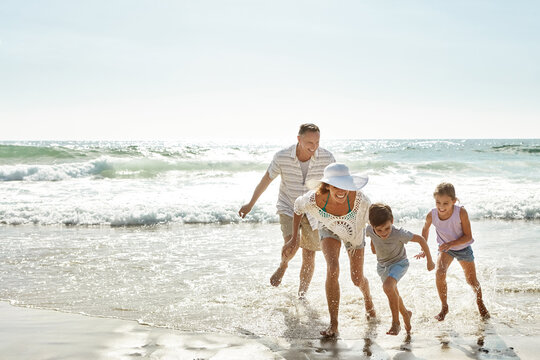 Running, water splash and happy family at beach with fun, bonding or freedom on summer, vacation and holiday. Travel, energy or kids with parents at ocean for adventure, journey or games in Florida