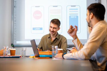 Group of business people sitting in a meeting room discussing a design for a smartphone application.