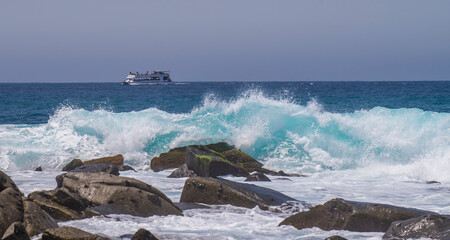 Fun on a tourist boat sailing in the Pacific Ocean through los cabos in front of the beaches of Cabo San Lucas with waves crashing on the rocks. summer vacation season. MEXICO