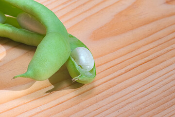 Broad beans, close up. Nutrition diet concept image. Macro photo of green bean grain in pod. Bean on wooden table.