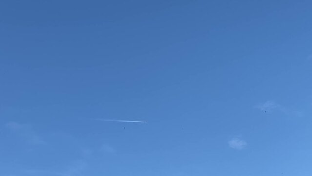 Airplane creates a jet stream in a clear, blue sky on a sunny day.
