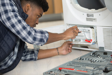 repairman repairing washing machine in the kitchen